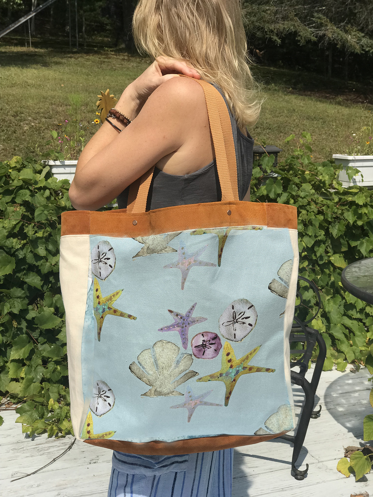 This coastal chic fashion leather & canvas tote features a whimsical watercolor painting of seashells. Handcrafted with love and attention to detail.